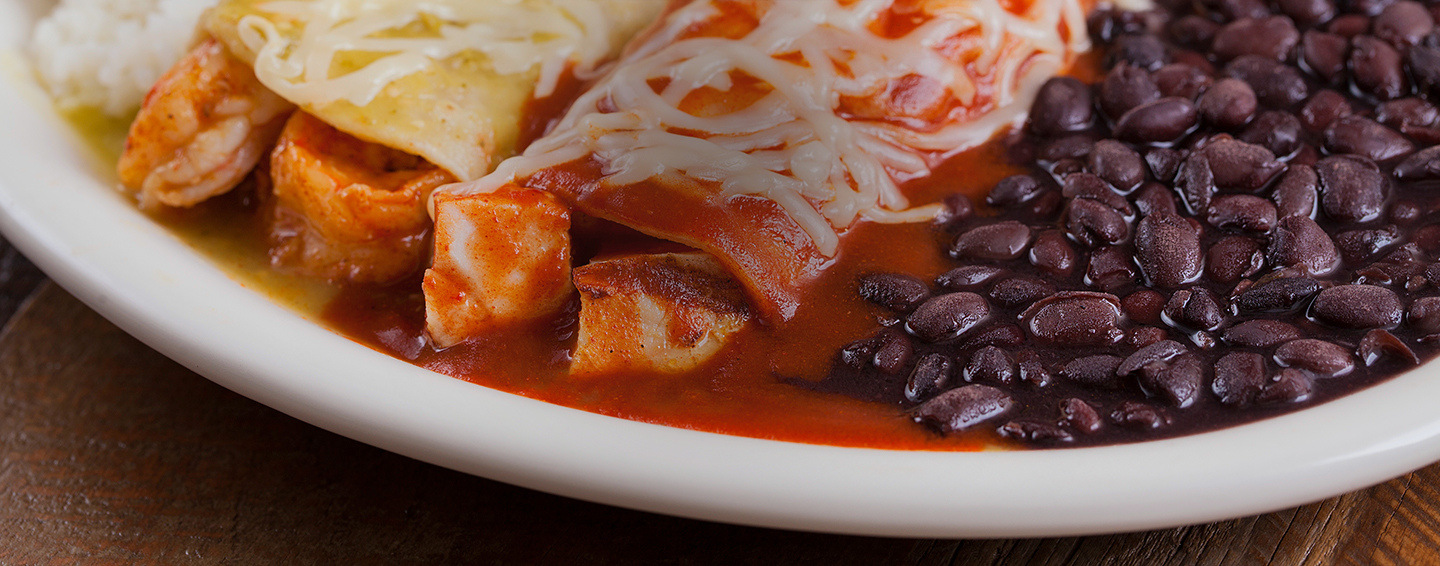 An enchilada combo served with rice and beans