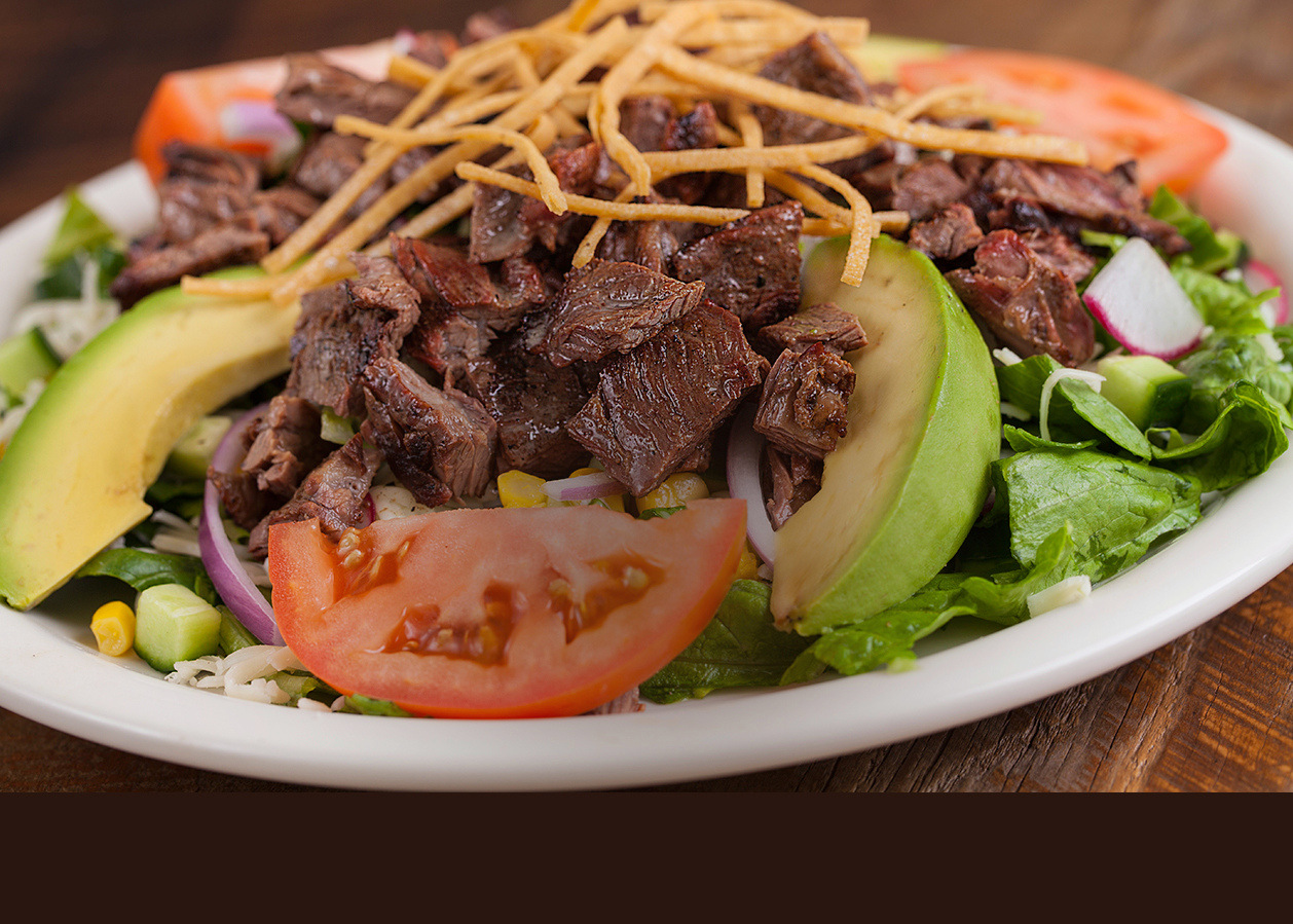 A Baja salad topped with grilled steak and avocado