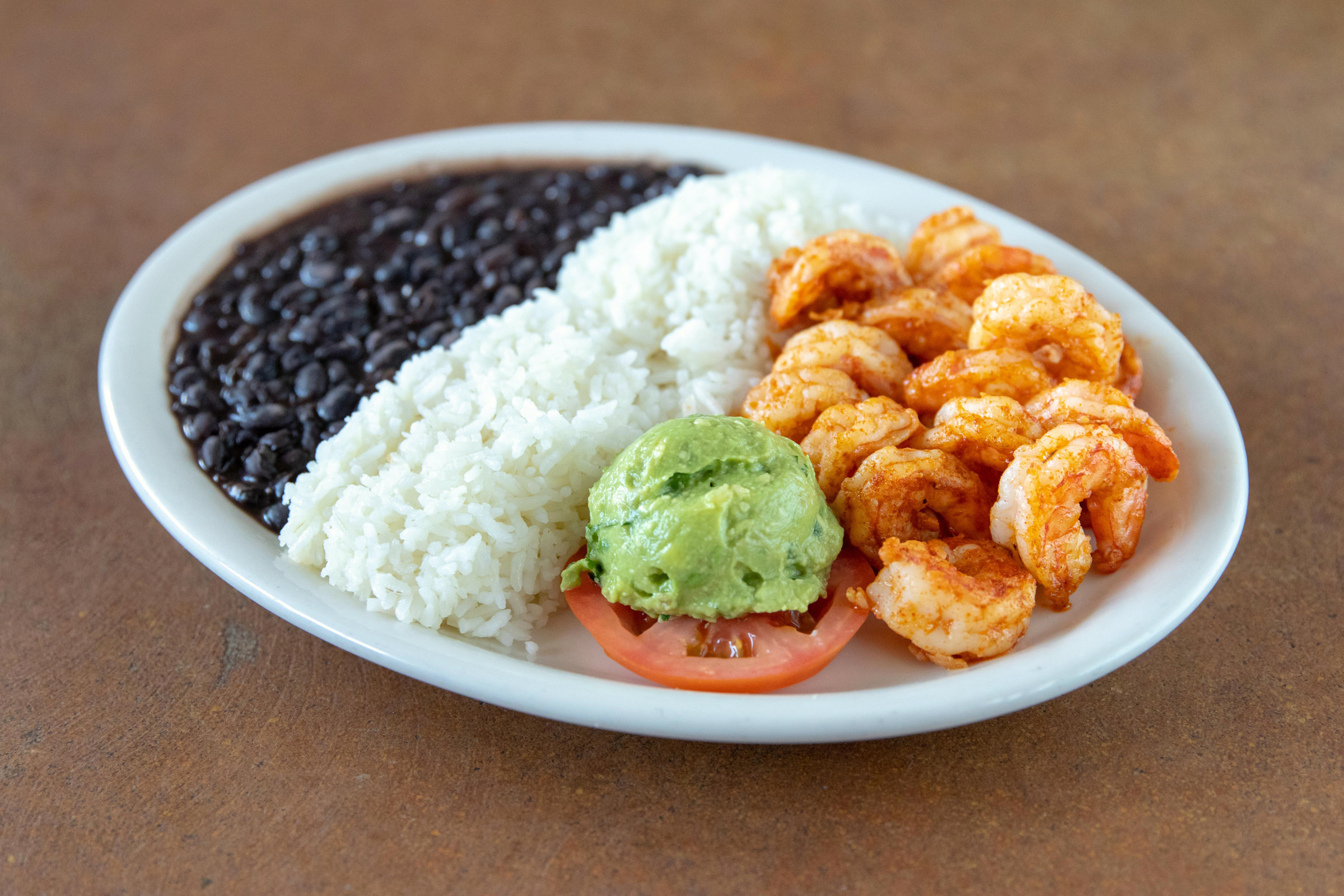A shrimp platter with rice, black beans and guacamole