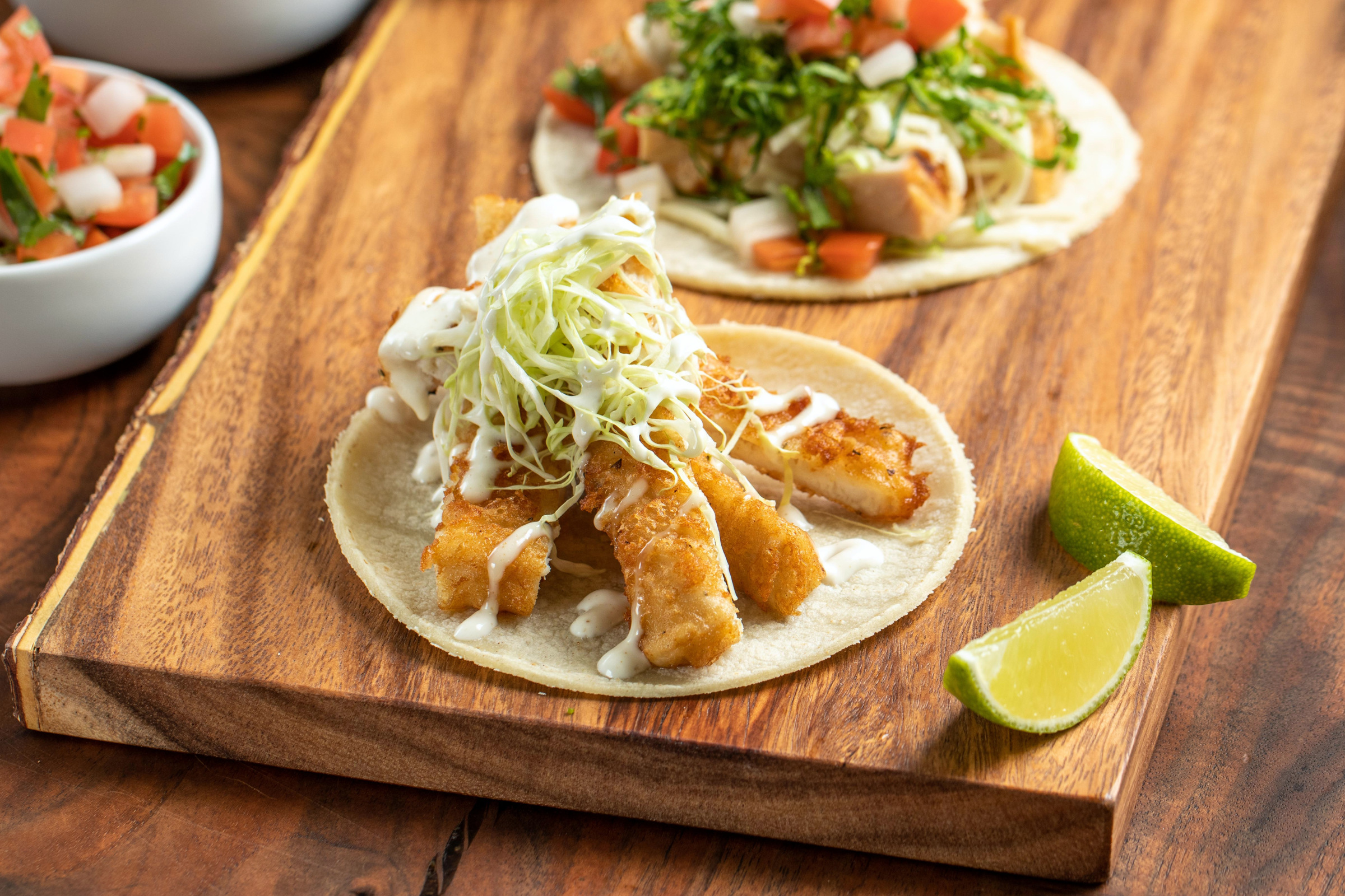 Baja fish tacos served on a wooden board with fresh lime